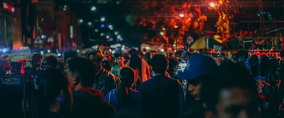 A bustling street market at night with crowds and vibrant streetlights.